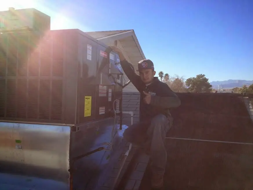 HVAC technician performing AC Tune-Up on a rooftop unit in Orchard Mesa
